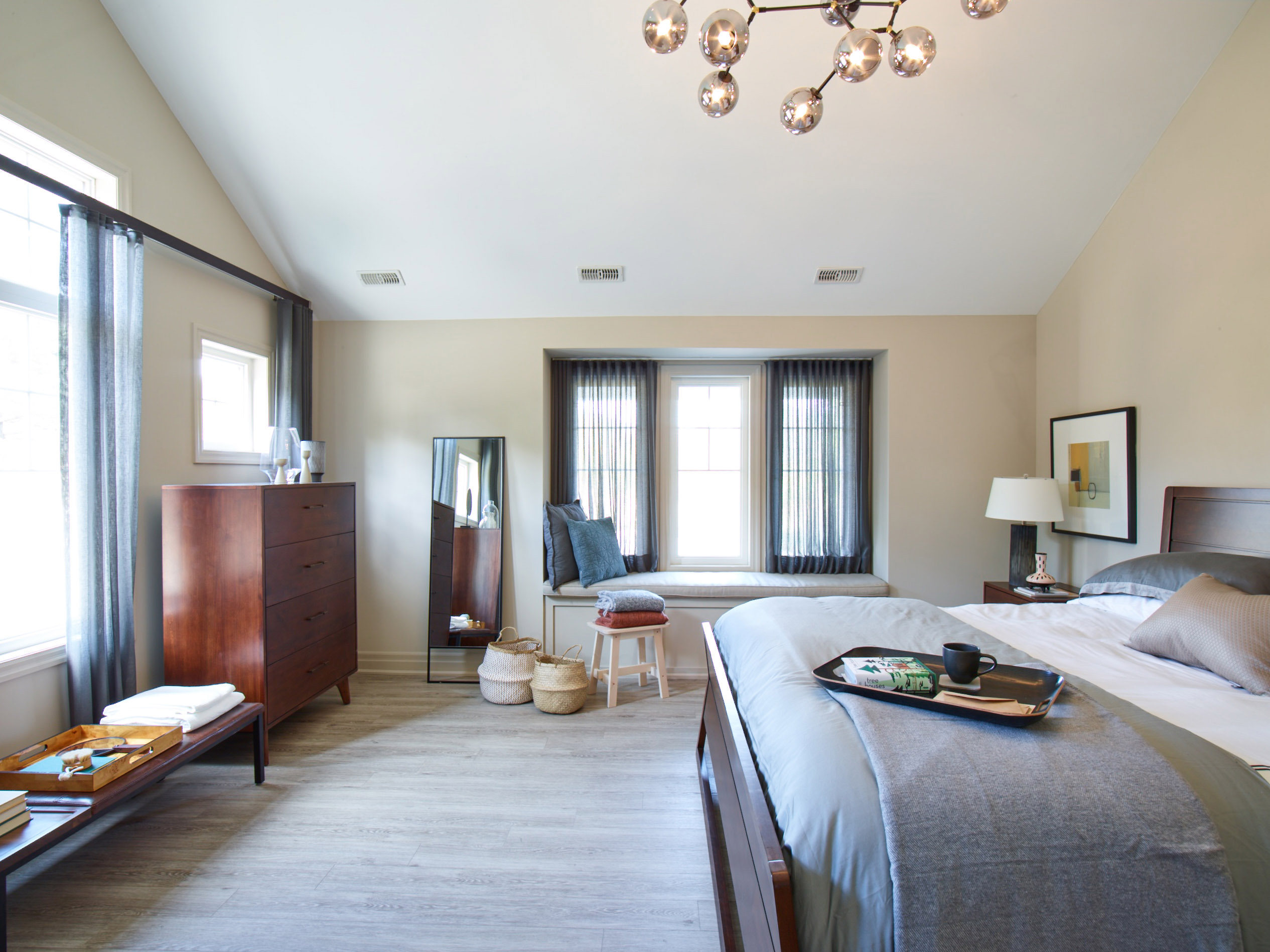 Oak Bay bedroom with window with bench seat, modern light fixture, and grey bedding