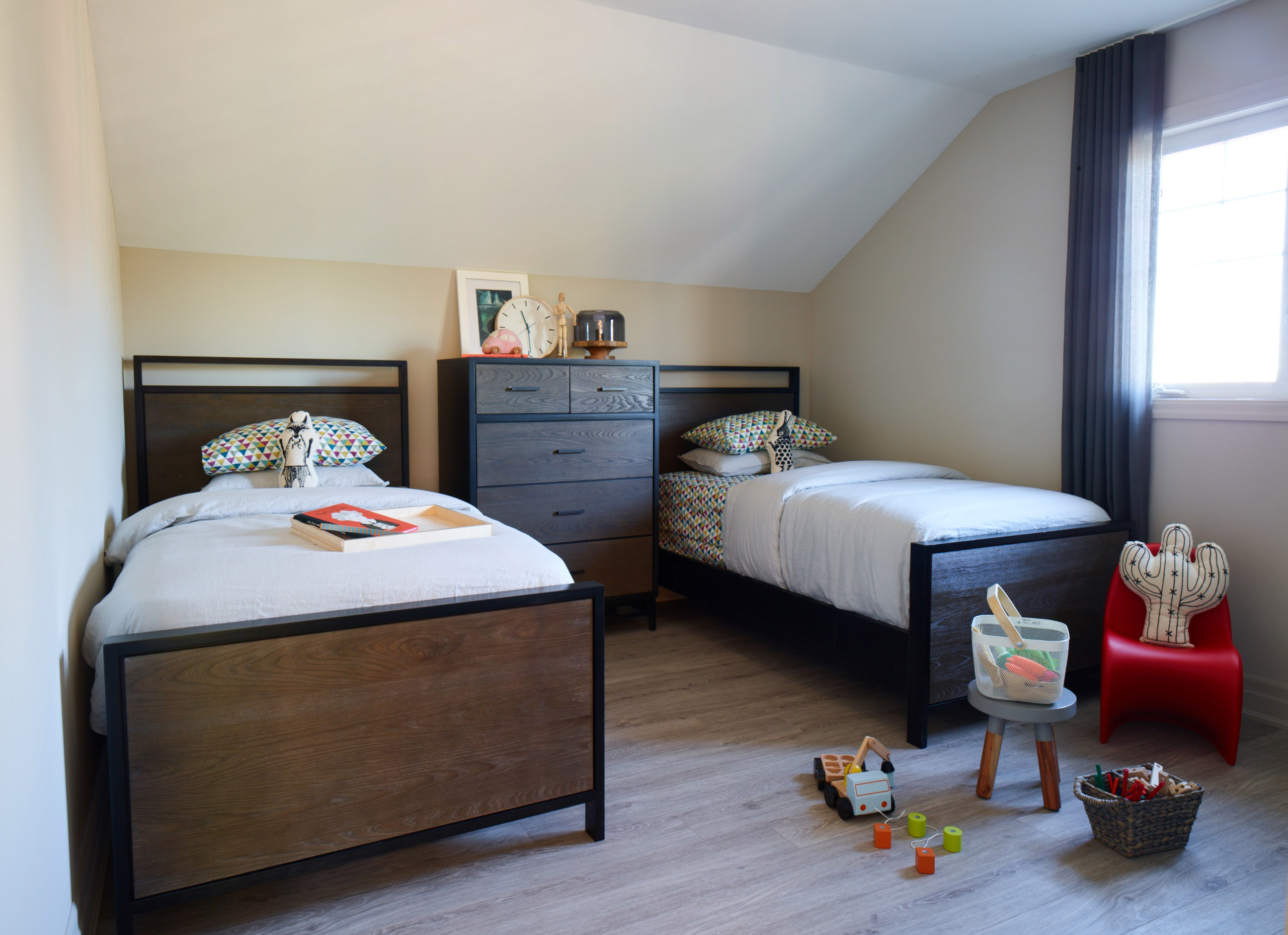 Oak Bay children's bedroom with two single beds with dresser in between, and pitched ceiling