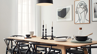 Modern Scandi dining room with large wood table, black wood chairs, and black and white accessories